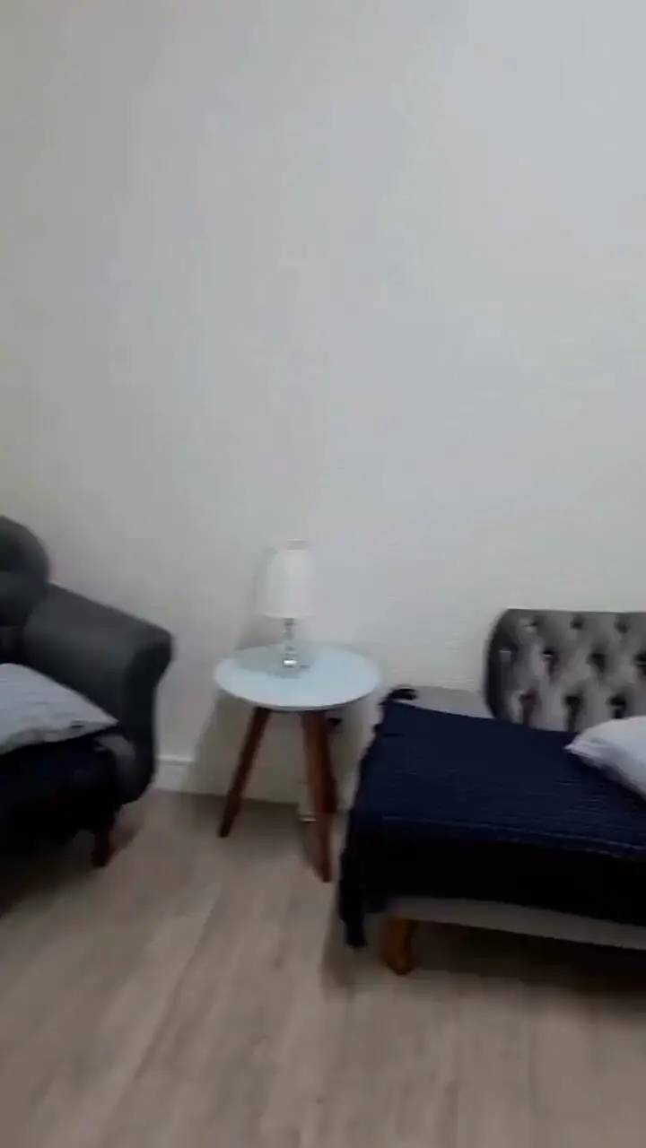 Sala de atendimento de psicologia, com poltronas, abajur e piso de madeira
